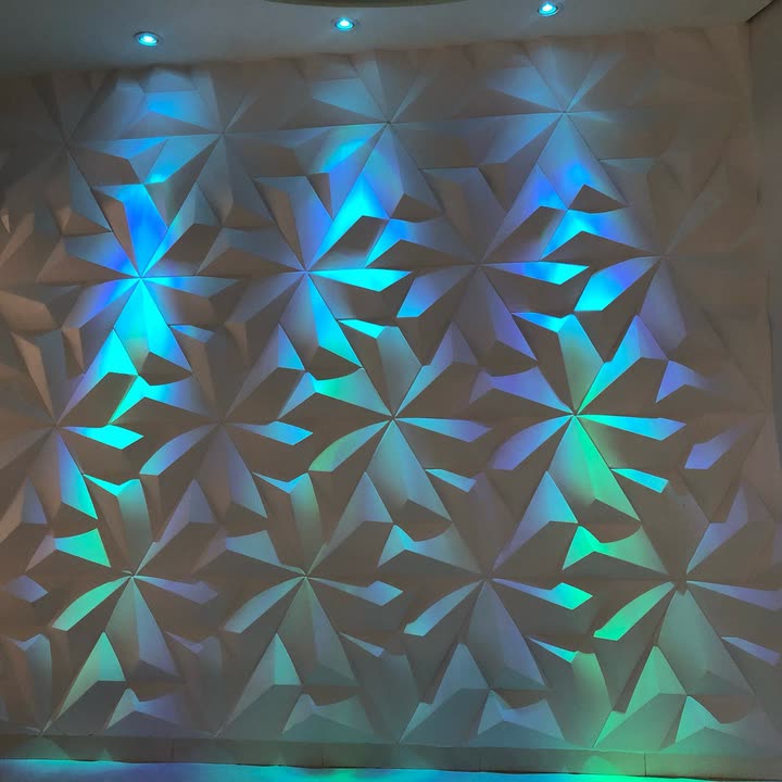 Detalhe do painel branco de relevo triangular banhado por luz magenta e violeta.
