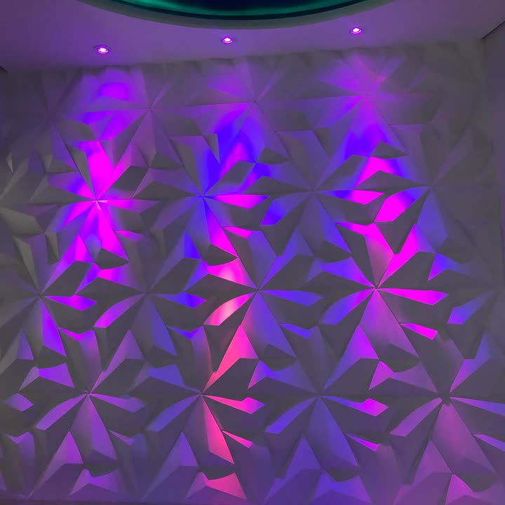 Detalhe do painel branco de relevo triangular banhado por luz verde e âmbar.