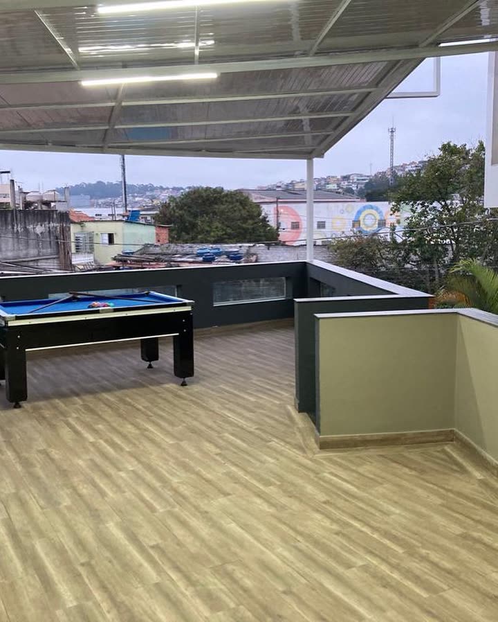 Terraço coberto no pavimento superior, com mesa de bilhar e vista aberta para os telhados do bairro.